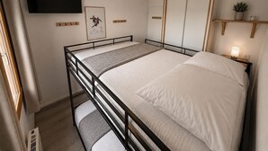 A single bed with a headboard, a bedside table with a lamp, a mounted TV, a framed picture, and a small shelf with a plant. - Le Nid des 3 Sommets - Proche station de ski (Villarembert)