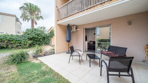 A patio area with outdoor furniture, a palm tree, and a view of the neighboring building. - Le Cosy Canétois - A 20 min de la plage (Canet-en-Roussillon)