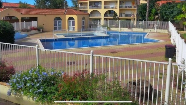 A hotel with a swimming pool, a fenced garden area, and a two-story building with balconies. - Le Cosy Canétois - A 20 min de la plage (Canet-en-Roussillon)