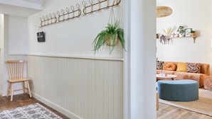 A hallway with a wooden chair, a hanging plant, and a wall-mounted rack with a 'WiFi Code' sign. - Le Logis du Clergé - Grande maison pour 15p (Lassy)