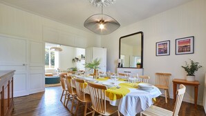 A dining area with a large table set for a meal, wooden chairs, a chandelier, and a mirror on the wall. - Le Logis du Clergé - Grande maison pour 15p (Lassy)