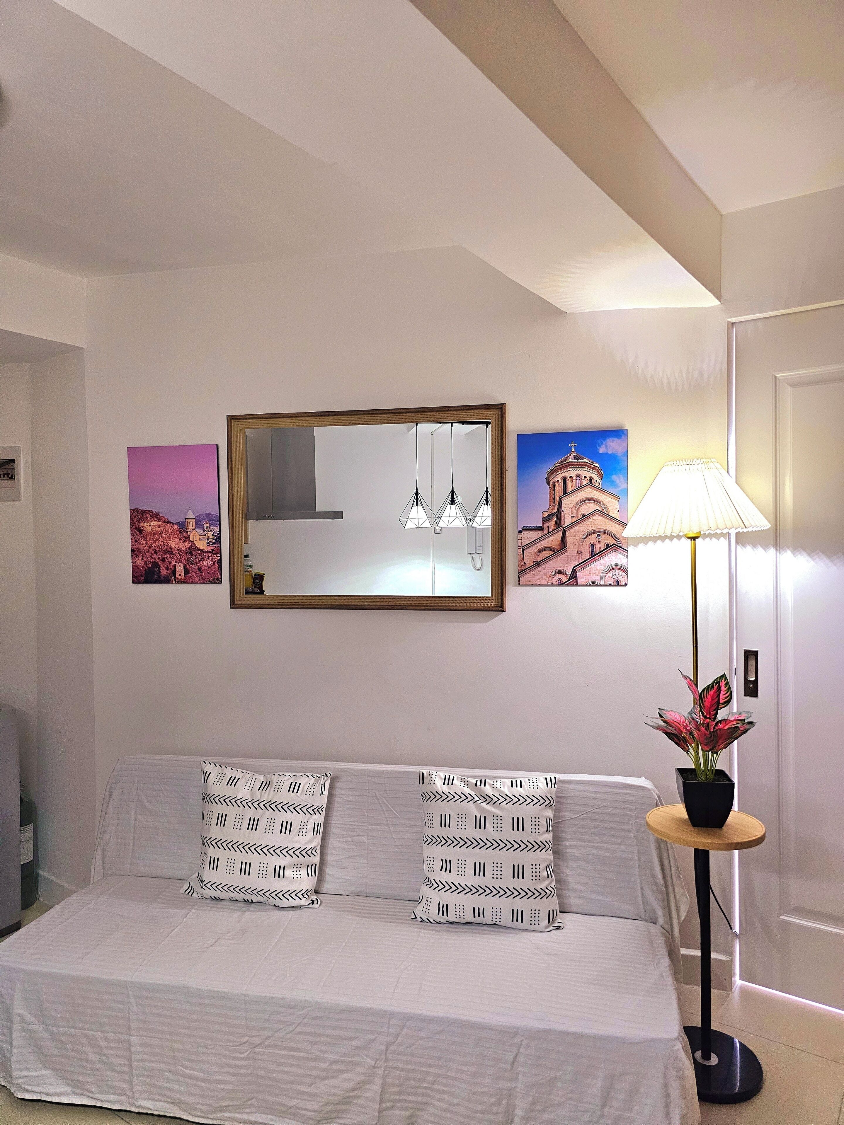 A hotel room with a bed, a mirror, and two framed pictures on the wall.