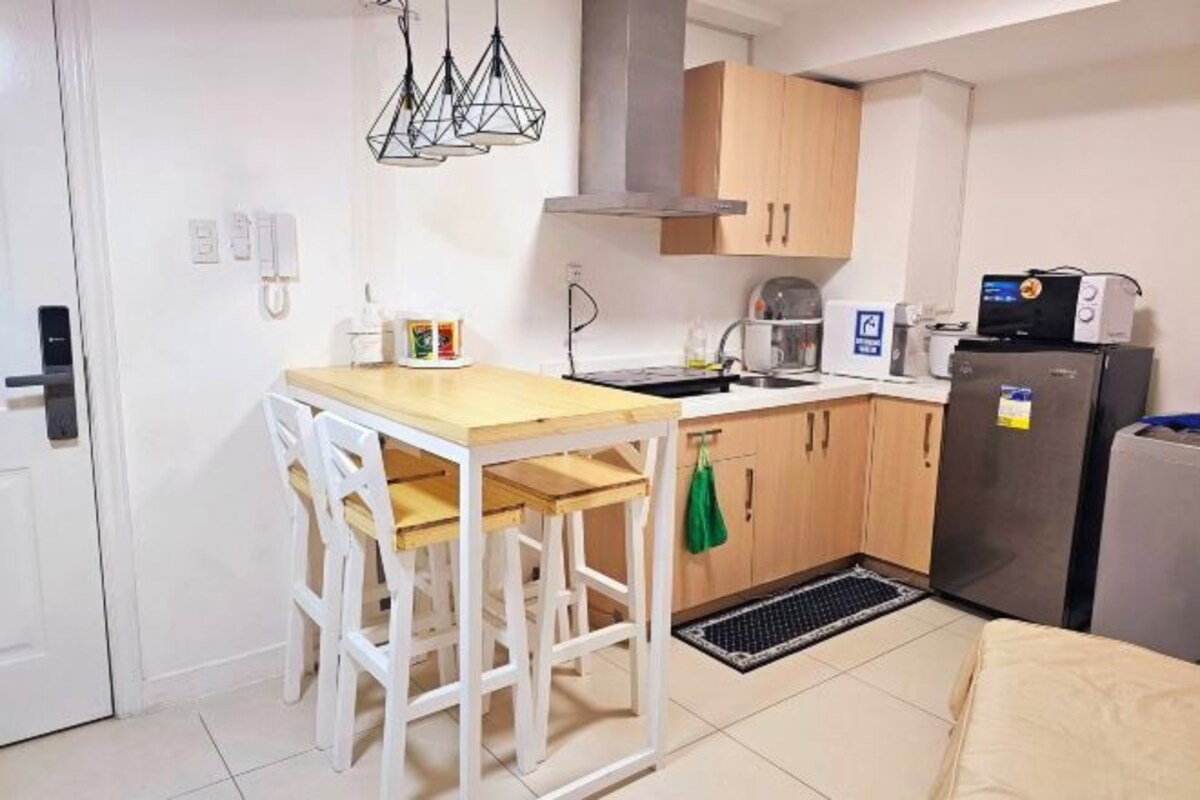 A compact kitchen with a wooden table and chairs, a sink, a stove, and a refrigerator.