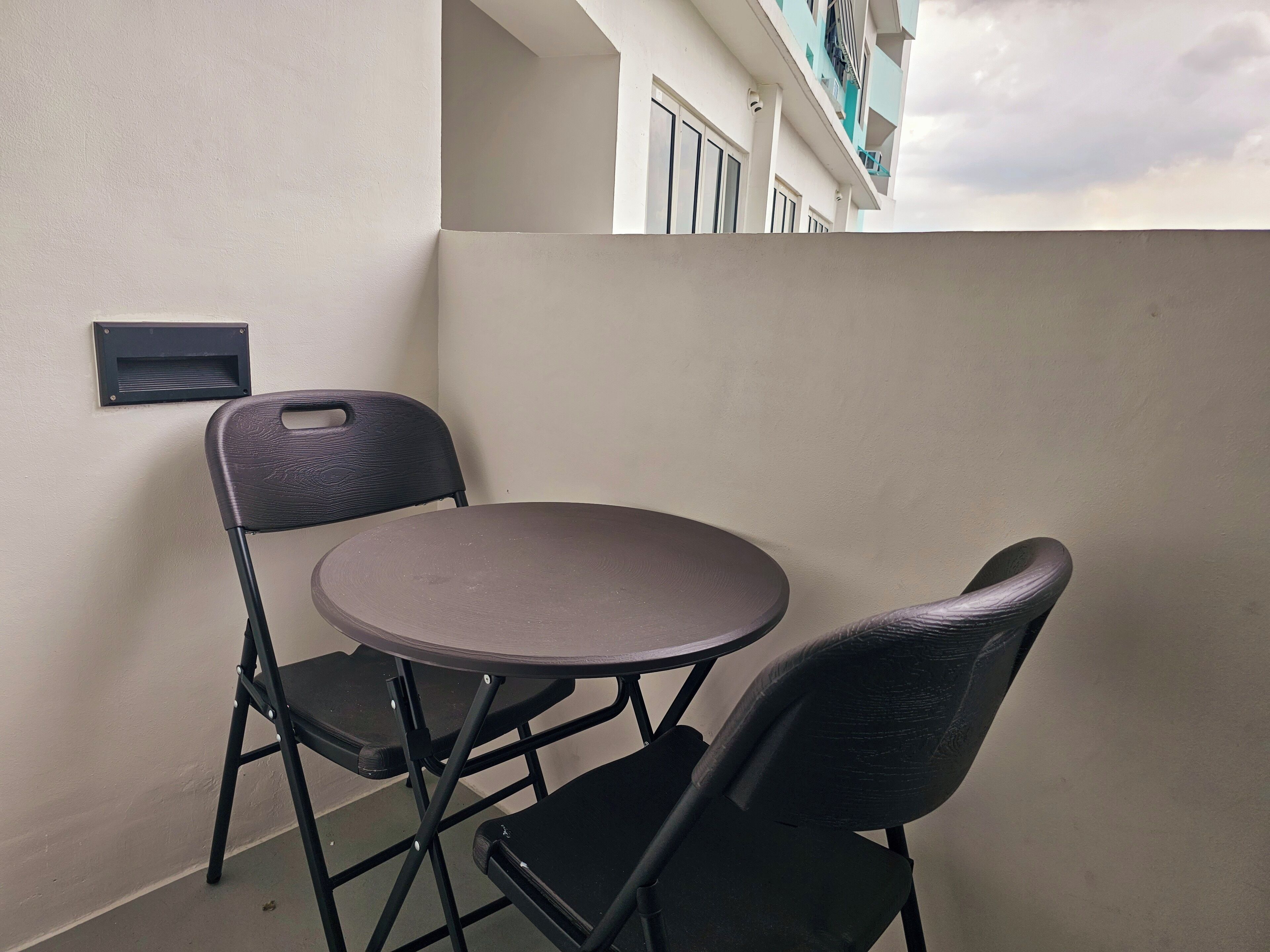 Een klein balkon met een ronde tafel en twee stoelen.
