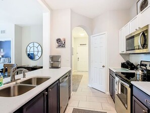 A modern kitchen with stainless steel appliances, a double sink, and a large mirror. - Enchanting Jedi Condo at Windsor Hills, By Disney (Kissimmee)