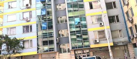 Un immeuble à plusieurs étages doté d’une architecture moderne, caractérisé par de grandes fenêtres et des unités de climatisation.