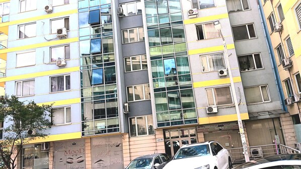 A multi-story building with a modern architectural design, featuring large windows and air conditioning units.