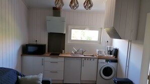 Cocina compacta con lavadora, lavaplatos, microondas y cafetera.