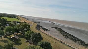A coastal area with a sandy beach, picnic areas, and a clear sky.