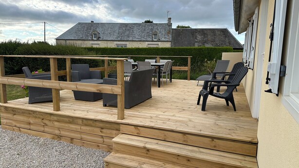 Una terraza de madera con mobiliario exterior, incluyendo sofás, sillas y una mesa.