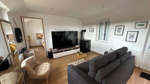 Una sala de estar moderna con un televisor de pantalla plana grande, un sofá, un sillón y una chimenea.