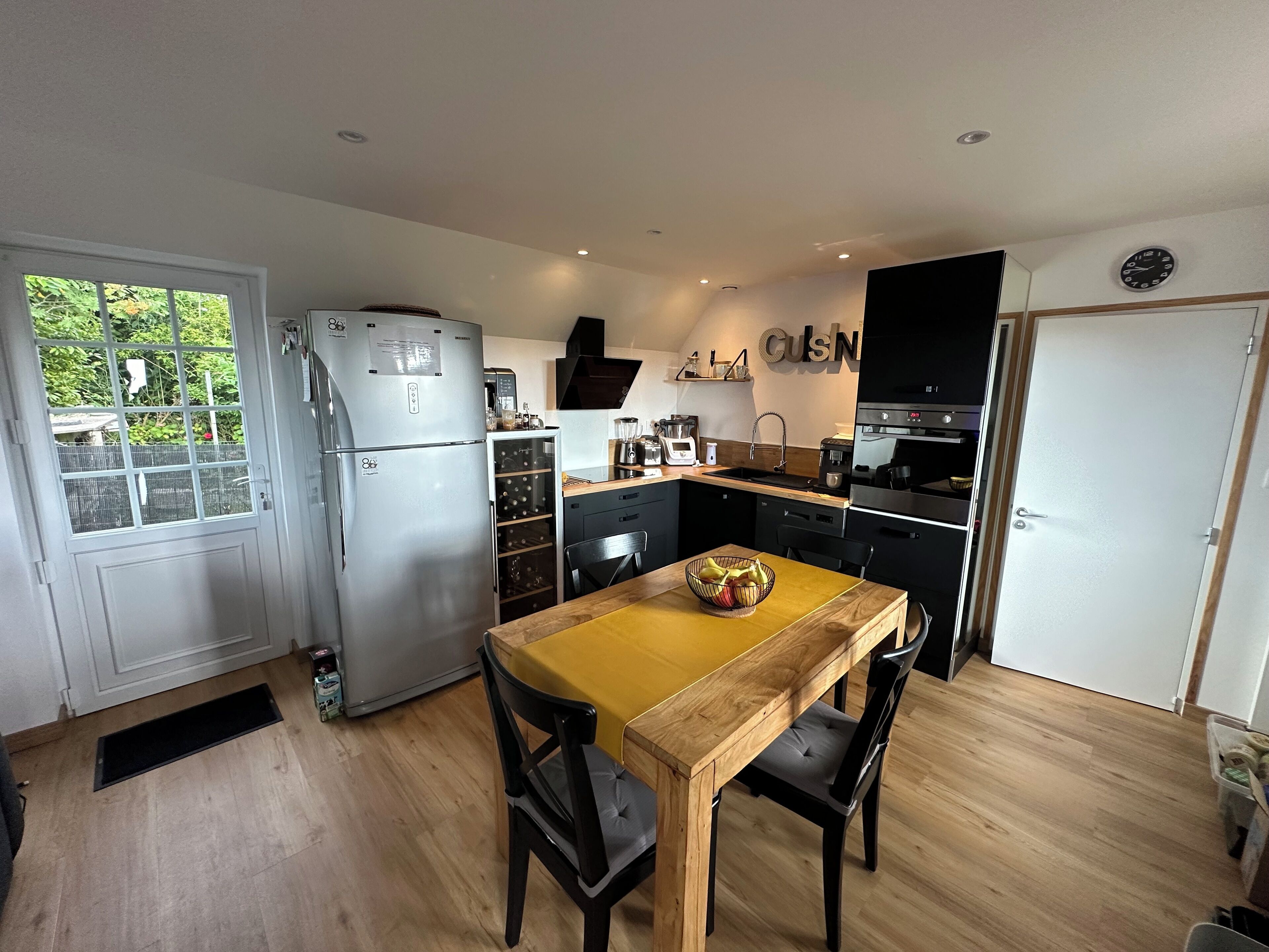 Una cocina compacta con comedor, un refrigerador, un horno empotrado y un lavamanos.