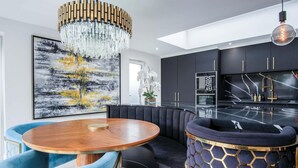 Une cuisine moderne avec un plan de travail noir, une table ronde en bois et un banc recouvert d’un tissu bleu.
