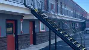 A multi-story motel with a central staircase, a fire hydrant, and a parking lot. - Travelers Rest Motel (Birmingham)