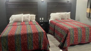 Two single beds with headboards, each with a bedside table and a wall-mounted light. - Travelers Rest Motel (Birmingham)