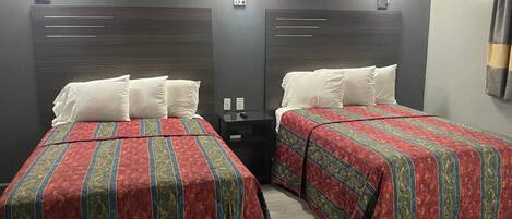 Two single beds with headboards, each with a bedside table and a wall-mounted light.