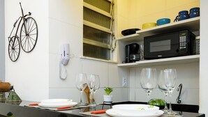 A modern kitchen with a black countertop, white and yellow tiles, a bicycle mounted on the wall, and orange bar stools. - BR-96 (Rio de Janeiro)