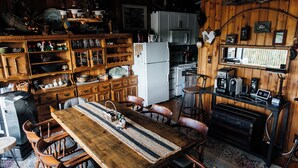 Una cocina rústica con gabinetes de madera, un refrigerador y un comedor con una mesa larga y sillas.