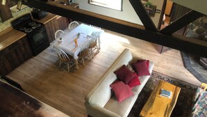A dining area with a white table and chairs, a sofa with red cushions, and a wooden coffee table. - Glacier National Park central location. Many Glacier, St. Mary, and Two Medicine (Babb)