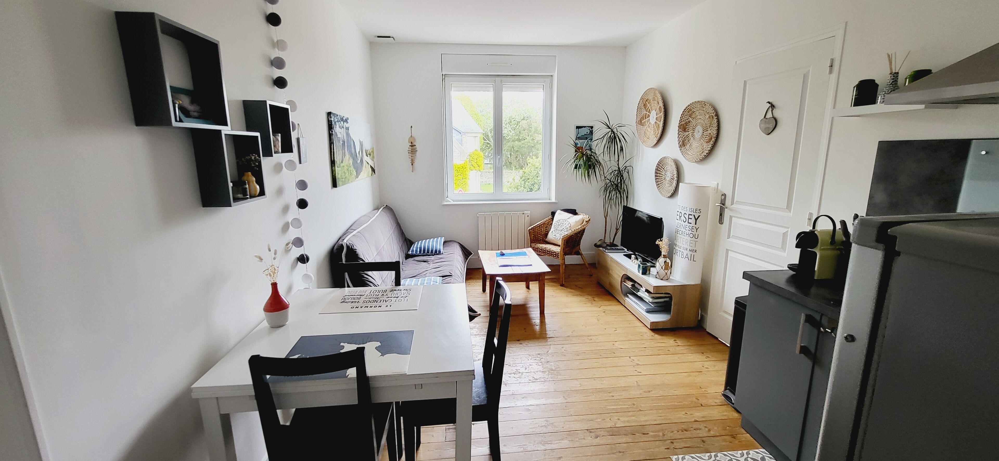 Cocina compacta con comedor, piso de madera y ventana que deja entrar luz natural.