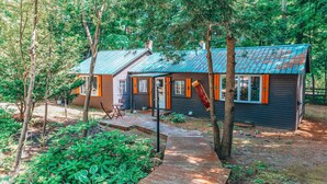 Une cabane avec un toit en métal, entourée d’arbres et dotée d’une terrasse en bois.