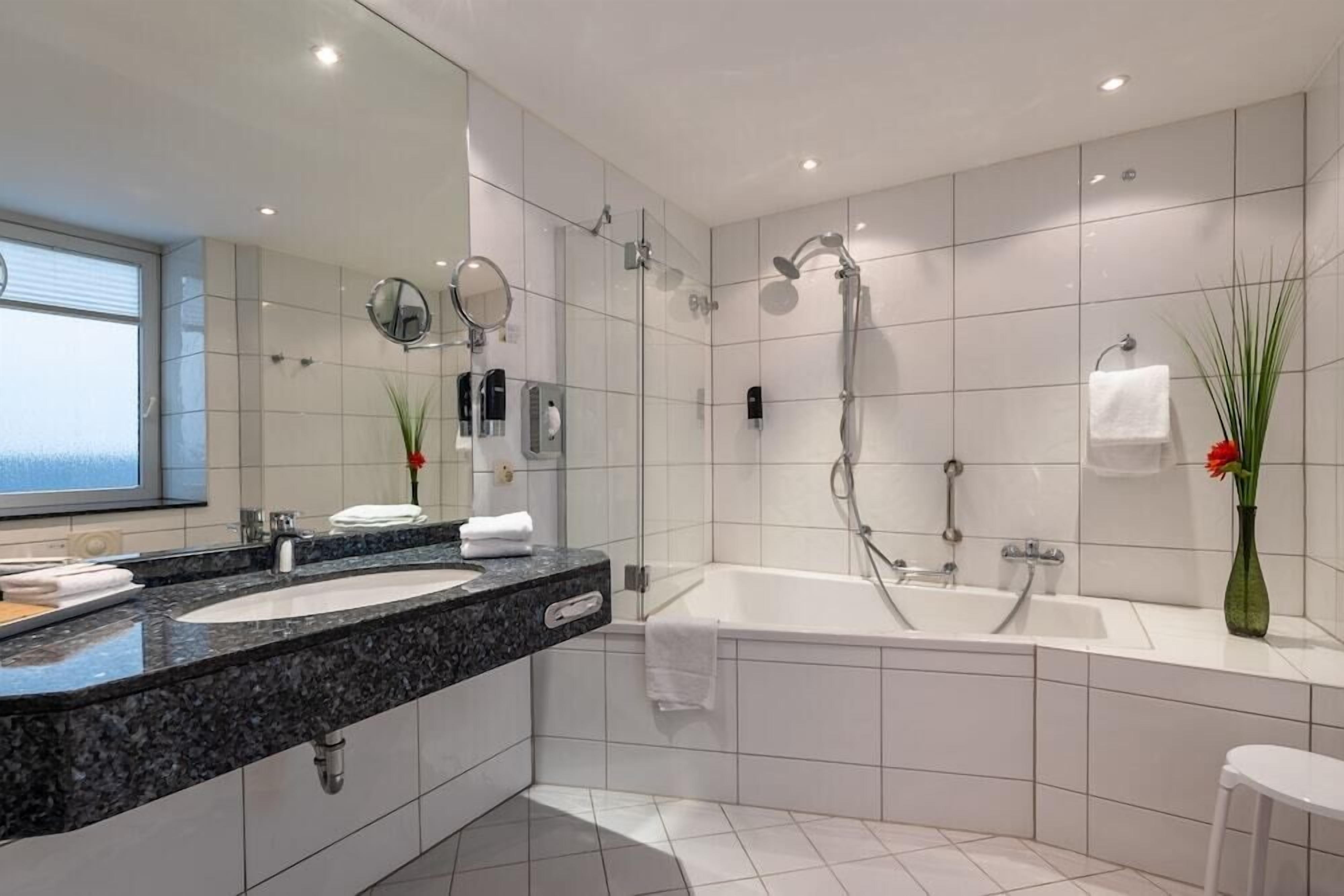 Un baño moderno con lavamanos doble, una bañera grande y una ducha.