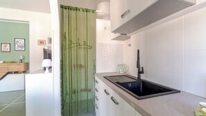 Eine moderne Küche mit einem schwarzen Spülbecken, weißen Schränken und einem grünen Vorhang.