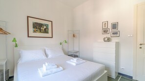 Ein Hotelzimmer mit Bett, Nachttisch, Kleiderschrank und einem gerahmten Bild an der Wand.