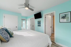 A bedroom with a bed, a ceiling fan, a TV, and a sign that says "Let's go on a sunset." - Hazel Mae's Hideaway (Gulf Shores)