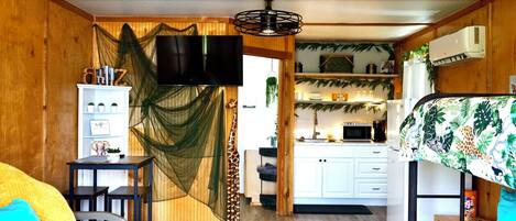 A cozy room with a bed, a desk, and a kitchenette.