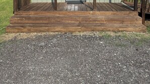 Ein kleines, eingeschossiges Gebäude mit Veranda, einer weißen Tür und einem Metalldach.