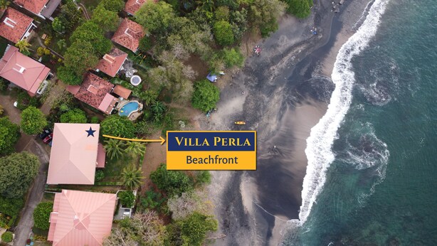 An aerial view of Villa Perla Beachfront, featuring a sandy beach, ocean waves, and surrounding lush greenery. - Villa Perla ~ Beachfront getaway for two at Los Almendros de Ocotal. (Playas Del Coco)