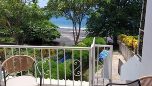 A balcony with wicker chairs, a view of the beach, and a gate leading to a pool area. - Villa Perla ~ Beachfront getaway for two at Los Almendros de Ocotal. (Playas Del Coco)