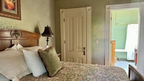 Ein Schlafzimmer mit einem blumigen Bettüberwurf, einem hölzernen Kopfteil und einem gerahmten Bild an der Wand.