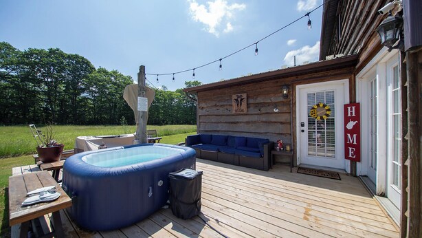 En træterrasse med jacuzzi, udendørs møbler og en velkomstskilt.