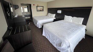 Ein Hotelzimmer mit zwei Betten, einem Schreibtisch, einem Stuhl, einem Fernseher und einem Badezimmer.