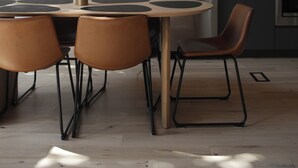 Une cuisine moderne avec une grande fenêtre, une table à manger ronde entourée de chaises et un plafond en bois.
