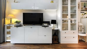 Een moderne keuken met een centraal eiland, een flatscreen televisie en een kast met glazen deuren.