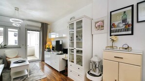 Een moderne woonkamer met een bank, een salontafel, een televisie en een eethoek met een kast en een dressoir.