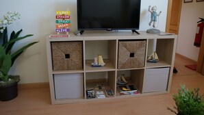 Un téléviseur posé sur un meuble en bois, avec des paniers en osier et des statuettes à proximité.