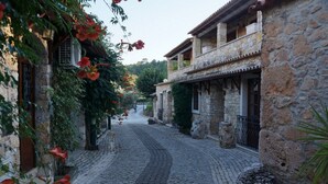 Une rue pavée bordée d’immeubles en pierre dotés de balcons et de fenêtres, qui mène à un point de vue lointain.
