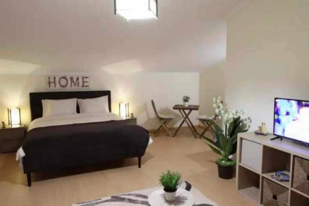A bedroom with a bed, a TV, a desk, and a chair.
