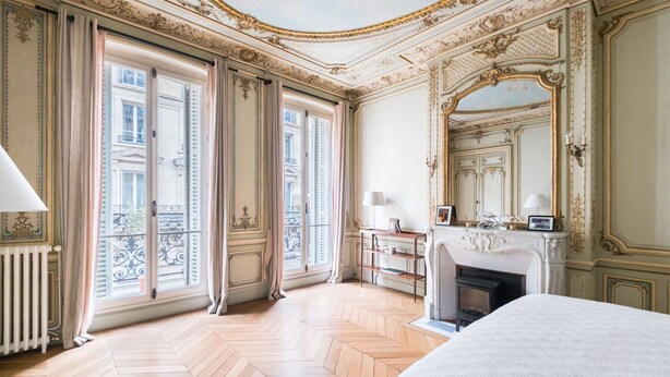 Une chambre à coucher luxueuse, dotée d’un grand lit, d’une cheminée et d’une décoration raffinée.