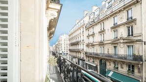 Une rue étroite, bordée de bâtiments de chaque côté, avec des balcons et des éléments architecturaux décoratifs.