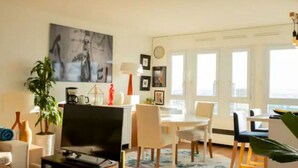 Ein modernes Wohnzimmer mit einem Flachbildfernseher, einem Couchtisch, einer Couch und einem Essbereich mit Stühlen und einem Tisch.