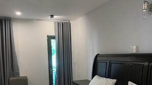 Hotellihuone, jossa on sänky, tuoli, työpöytä ja ikkuna, jossa on verhot.