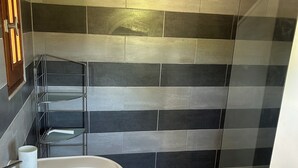 A bathroom with a white sink, a glass shower enclosure, and a tiled shower wall.
