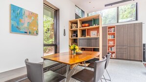 A modern kitchen with a wooden dining table, four chairs, and built-in shelves with books and decorative items.