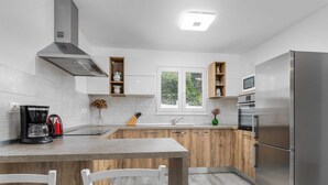 Une cuisine moderne dotée d’un îlot central, d’appareils électroménagers en acier inoxydable et de meubles de rangement en bois.