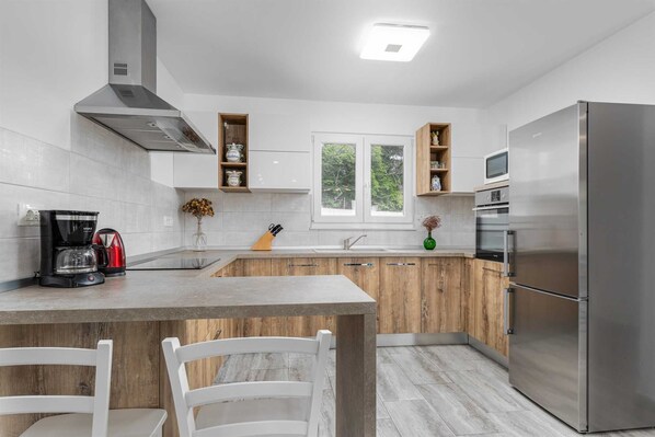 A modern kitchen with a central island, stainless steel appliances, and wooden cabinetry.